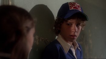 Movie still from “Prom Night” (1980), directed by Paul Lynch – A young boy wearing a baseball cap stares at another young boy; Close Up shot, Over the shoulder angle