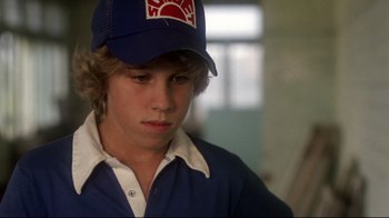 Movie still from “Prom Night” (1980), directed by Paul Lynch – A young man wearing a baseball cap and a blue shirt; Close Up shot, Over the shoulder angle