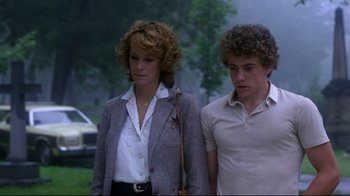 Movie still from “Prom Night” (1980), directed by Paul Lynch – A woman and a young man are walking in a park; Medium shot, Low angle