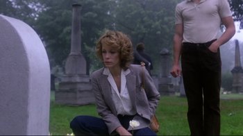 Movie still from “Prom Night” (1980), directed by Paul Lynch – A woman kneeling down in the grass holding a white rose; Medium shot, Over the shoulder angle