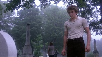 Movie still from “Prom Night” (1980), directed by Paul Lynch – A man standing in front of a tree with trees in the background; Medium shot, Low angle