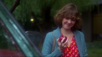 Movie still from “Prom Night” (1980), directed by Paul Lynch – A woman holding an apple while standing next to a car; Close Up shot, Over the shoulder angle