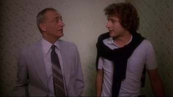Movie still from “Prom Night” (1980), directed by Paul Lynch – A man in a suit talking to a young man; Medium shot, Over the shoulder angle