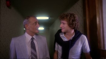Movie still from “Prom Night” (1980), directed by Paul Lynch – A man and a boy standing next to each other in a hallway; Medium shot, Low angle