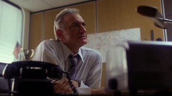 Movie still from “Prom Night” (1980), directed by Paul Lynch – An older man sitting at a desk in an office; Close Up shot, Low angle