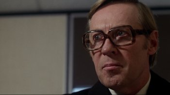 Movie still from “Prom Night” (1980), directed by Paul Lynch – An older man wearing glasses looking at the camera; Close Up shot, Low angle