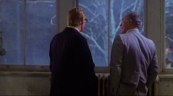 Movie still from “Prom Night” (1980), directed by Paul Lynch – Two men are standing in front of a window; Medium shot, Over the shoulder angle