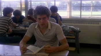 Movie still from “Prom Night” (1980), directed by Paul Lynch – A man sitting at a table reading a book; Medium shot, Over the shoulder angle