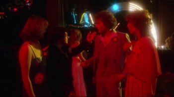 Movie still from “Prom Night” (1980), directed by Paul Lynch – A group of people standing in a room at night; Wide shot, Over the shoulder angle