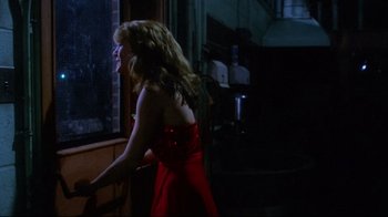 Movie still from “Prom Night” (1980), directed by Paul Lynch – A woman in a red dress looking out of a window; Medium shot, Over the shoulder angle