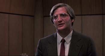 Movie still from “Psycho II” (1983), directed by Richard Franklin – A man in a suit and tie wearing glasses; Close Up shot, Low angle