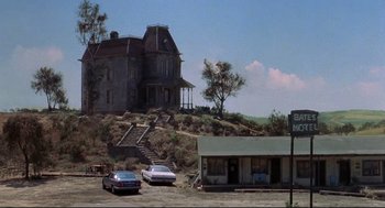 Movie still from “Psycho II” (1983), directed by Richard Franklin – An old house with a car parked in front of it; Extreme Wide shot, Low angle