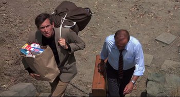 Movie still from “Psycho II” (1983), directed by Richard Franklin – Two men walking on the beach with their luggage; Medium shot, High angle