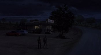 Movie still from “Psycho II” (1983), directed by Richard Franklin – Two people standing in the dark near a building; Extreme Wide shot, Low angle