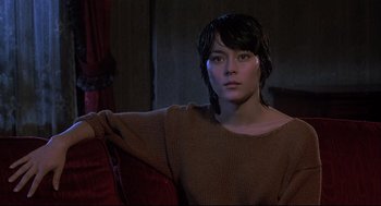 Movie still from “Psycho II” (1983), directed by Richard Franklin – A woman in a brown sweater sitting on a red couch; Medium shot, Low angle