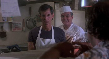 Movie still from “Psycho II” (1983), directed by Richard Franklin – Two men wearing aprons in a kitchen preparing food; Medium shot, Over the shoulder angle