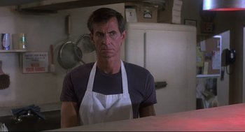 Movie still from “Psycho II” (1983), directed by Richard Franklin – A man wearing an apron in a kitchen; Close Up shot, Low angle