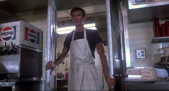 Movie still from “Psycho II” (1983), directed by Richard Franklin – A man wearing an apron standing in a kitchen; Medium shot, Low angle
