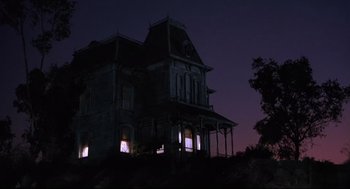 An old house with a clock lit up at night