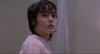 Movie still from “Psycho II” (1983), directed by Richard Franklin – A woman with wet hair and a pink shirt is looking at the camera; Close Up shot, Low angle