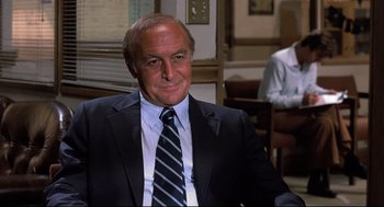 Movie still from “Psycho II” (1983), directed by Richard Franklin – An older man wearing a suit and tie; Medium shot, Over the shoulder angle