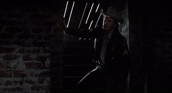 Movie still from “Psycho II” (1983), directed by Richard Franklin – A man in a cowboy hat standing on some stairs; Medium shot, Low angle