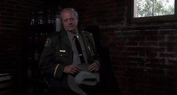 Movie still from “Psycho II” (1983), directed by Richard Franklin – An older man in a uniform holding a cowboy hat; Medium shot, Low angle