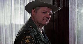 Movie still from “Psycho II” (1983), directed by Richard Franklin – A man wearing a sheriff's uniform and a cowboy hat; Close Up shot, Low angle