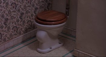 Movie still from “Psycho II” (1983), directed by Richard Franklin – A white toilet sitting in the corner of a bathroom; Wide shot, Overhead angle