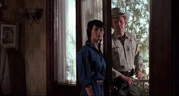 Movie still from “Psycho II” (1983), directed by Richard Franklin – A man and a woman standing next to each other in front of a window; Medium shot, Low angle