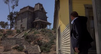 Movie still from “Psycho II” (1983), directed by Richard Franklin – A man standing outside of an old abandoned house; Wide shot, Low angle