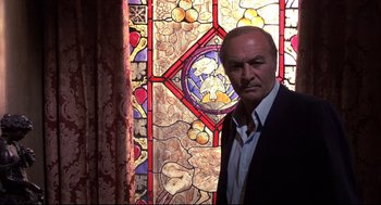 Movie still from “Psycho II” (1983), directed by Richard Franklin – A man standing in front of a stained glass window; Close Up shot, Low angle