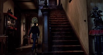 Movie still from “Psycho II” (1983), directed by Richard Franklin – A man walking down a staircase in a house; Wide shot, Low angle