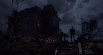 Movie still from “Psycho II” (1983), directed by Richard Franklin – A man standing on the steps outside of a dark house; Wide shot, Low angle