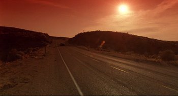 Movie still from “Psycho III” (1986), directed by Anthony Perkins – The sun is setting over a desert road; Extreme Wide shot, Low angle