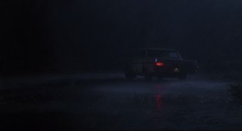 Movie still from “Psycho III” (1986), directed by Anthony Perkins – A car driving down a street in the dark; Extreme Wide shot, Low angle