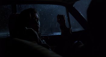 Movie still from “Psycho III” (1986), directed by Anthony Perkins – A man sitting in the driver's seat of a car at night; Medium shot, Over the shoulder angle