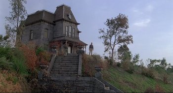 Movie still from “Psycho III” (1986), directed by Anthony Perkins – A man standing on the steps of an old house; Wide shot, Low angle