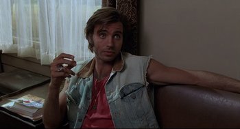 Movie still from “Psycho III” (1986), directed by Anthony Perkins – A man sitting on a couch holding a glass of wine; Close Up shot, Low angle