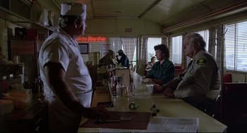 Movie still from “Psycho III” (1986), directed by Anthony Perkins – A group of people sitting at a counter in a restaurant; Wide shot, Over the shoulder angle