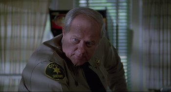 Movie still from “Psycho III” (1986), directed by Anthony Perkins – A man in a sheriff's uniform looking at the camera; Close Up shot, Low angle