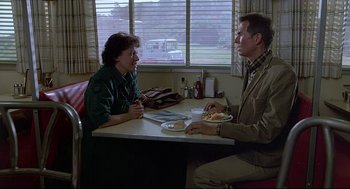 Movie still from “Psycho III” (1986), directed by Anthony Perkins – A man and a woman sitting at a dinner table; Medium shot, Over the shoulder angle