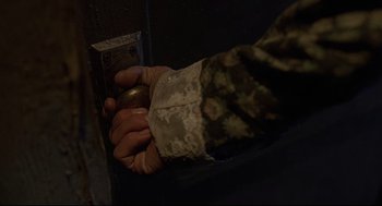 Movie still from “Psycho III” (1986), directed by Anthony Perkins – A man in a camouflage jacket is holding a metal object; Extreme Close Up shot, High angle