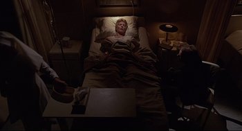 Movie still from “Psycho III” (1986), directed by Anthony Perkins – A man laying in a bed in a dark room; Wide shot, High angle