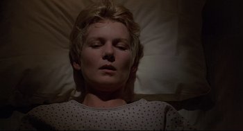 Movie still from “Psycho III” (1986), directed by Anthony Perkins – A woman laying in a bed with her eyes closed; Close Up shot, High angle