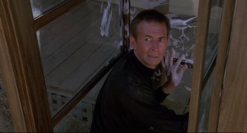 Movie still from “Psycho III” (1986), directed by Anthony Perkins – A man in a black shirt is standing in front of a window; Close Up shot, Low angle
