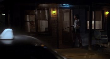 Movie still from “Psycho III” (1986), directed by Anthony Perkins – A woman walking in front of a building at night; Wide shot, Low angle
