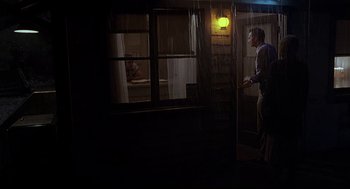 Movie still from “Psycho III” (1986), directed by Anthony Perkins – A man standing in front of a window in a dark room; Wide shot, Low angle