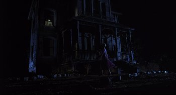 Movie still from “Psycho III” (1986), directed by Anthony Perkins – A person walking in front of a house at night; Wide shot, Low angle