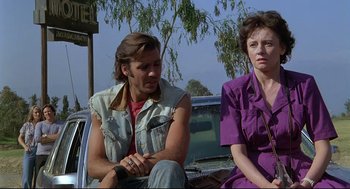 Movie still from “Psycho III” (1986), directed by Anthony Perkins – A man and a woman sitting next to each other on the back of a car; Medium shot, Low angle